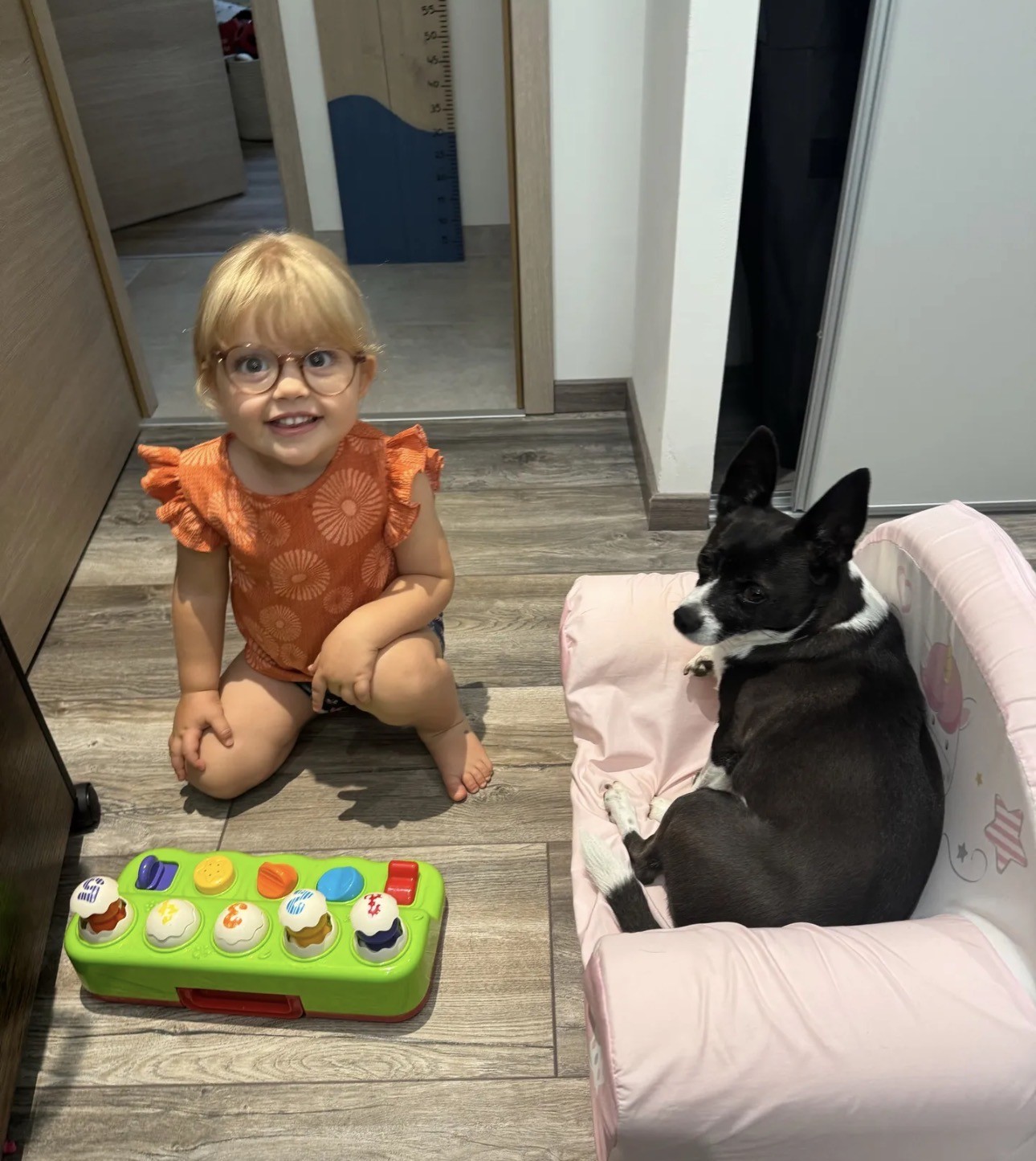 Anna souriante à côté d’un chien installé dans son panier.